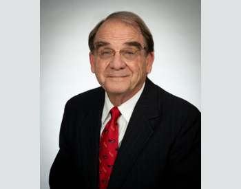 Older gentleman. Glasses. Black suit. Red tie.
